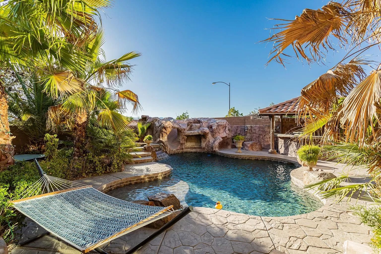 Resort-style backyard pool with rock waterfall and palms at a Lux Escape Rentals home